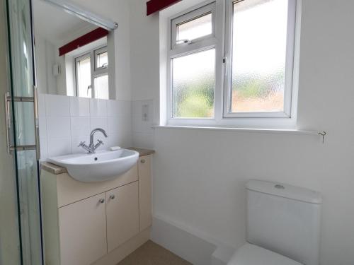 a bathroom with a sink and a toilet and a window at Thorncroft in West Bay