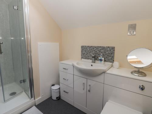 ein weißes Badezimmer mit Waschbecken und Spiegel in der Unterkunft Pebble Cottage Dunnscroft in Bridlington