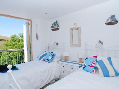 two beds in a white room with a window at 5 Prospect House in Beesands