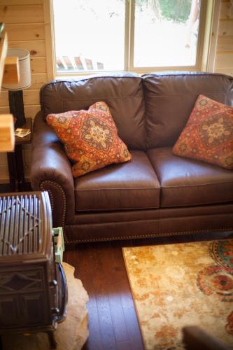a brown leather couch in a living room with pillows at The Ridge At Glacier - Luxury Cabins in Coram