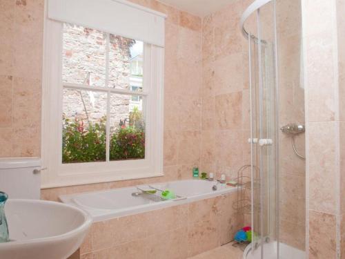 ein Badezimmer mit Badewanne und Waschbecken und einem Fenster in der Unterkunft The Cottage, 13 Clarence Hill in Dartmouth