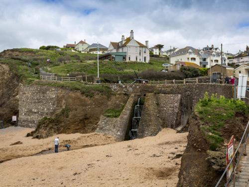 a man standing on a beach next to a retaining wall at 5 Chichester Court in Kingsbridge