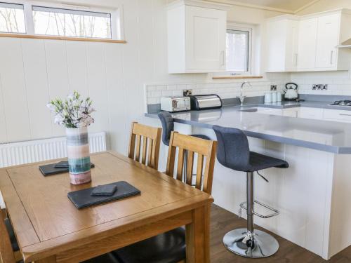a kitchen with a wooden table and a counter top at Woodpecker Lodge in Skipton
