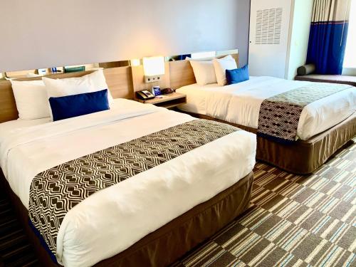 a hotel room with two beds and a couch at Microtel Inn & Suites by Wyndham Georgetown Delaware Beaches in Georgetown