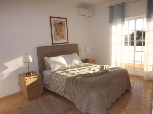 sypialnia z łóżkiem, 2 lampami i oknem w obiekcie Villa Mariamar w Albufeirze