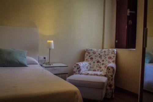 a bedroom with a bed and a chair and a lamp at El Descanso del Monje in La Drova