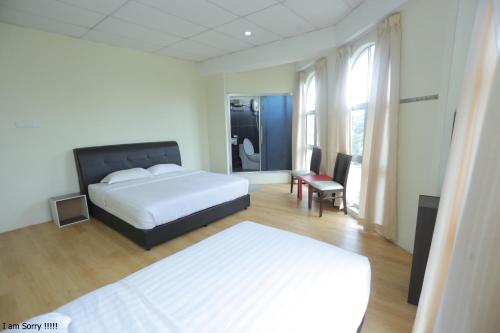 a bedroom with two beds and a chair and a table at JAM Hotel Kota Warisan Sepang @ ERL Salak Tinggi, KLIA 1-2 & F1 in Sepang