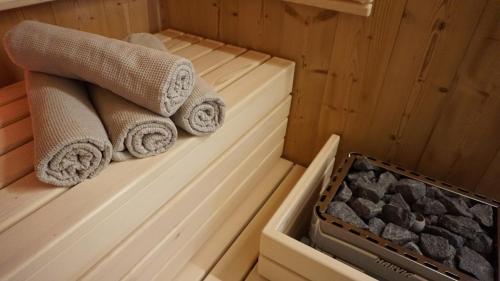 ARLBERGhome Komfort-Apartments & Privat-Sauna في والد ام ارلبرغ: ساونا مع المناشف وصينية من الصخور