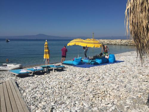 a group of people sitting on a beach under an umbrella at Agali 2 maizonette front of the sea in Akrogiali