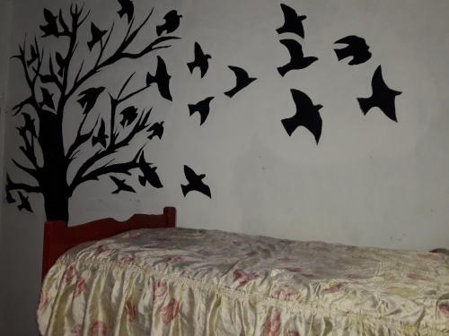un dormitorio con un árbol con pájaros en la pared en Lo de Charly en Villa Carlos Paz