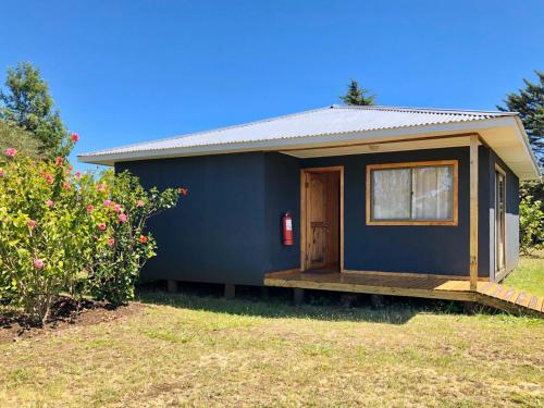 a blue tiny house with a porch in a yard at Rangi Moana in Hanga Roa