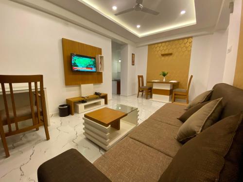a living room with a couch and a tv at Utsavam Hotel Apartments in Guruvāyūr