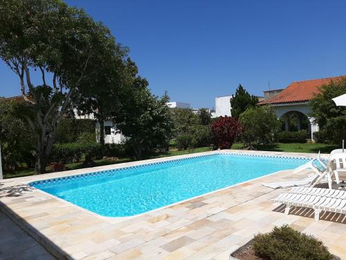 a swimming pool in a yard with two chairs next to it at Pousada Santa Fé in Aparecida