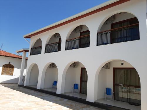 an exterior view of a white building with arches at Pousada Santa Fé in Aparecida