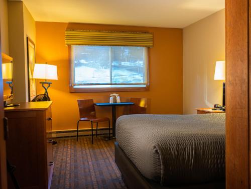 a hotel room with a bed and a table and a window at The Black Bear Lodge at Stratton Mountain Resort in Stratton Mountain
