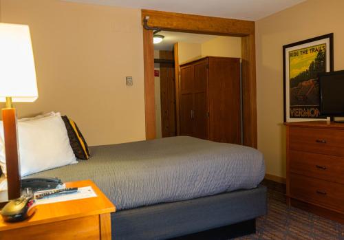 a bedroom with a bed and a desk with a lamp at The Black Bear Lodge at Stratton Mountain Resort in Stratton Mountain