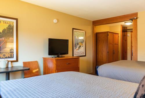 a hotel room with two beds and a flat screen tv at The Black Bear Lodge at Stratton Mountain Resort in Stratton Mountain