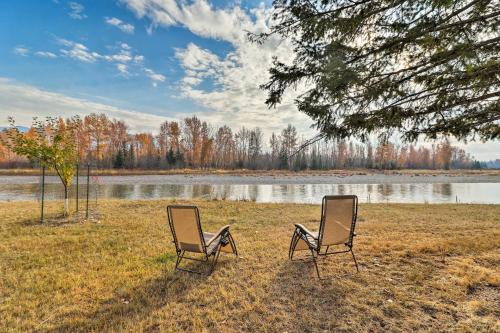 two chairs sitting in the grass next to a lake at Kalispell Riverfront Home by Glacier National Park in Kalispell