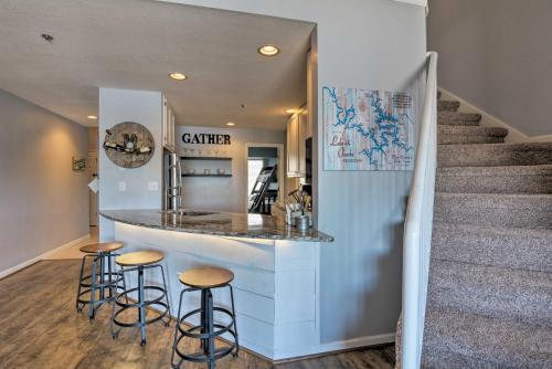 a kitchen with a counter with stools and a staircase at Deck, Pool and Views Lake of the Ozarks Condo in Kaiser