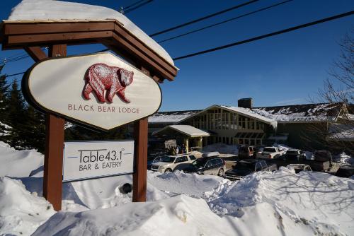a sign for a black bear lodge in the snow at The Black Bear Lodge at Stratton Mountain Resort in Stratton Mountain