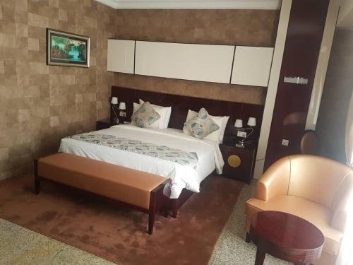 a bedroom with a large bed and a chair at Conference Hotel , Abeokuta in Abeokuta