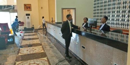 a man in a suit standing at a counter at Conference Hotel , Abeokuta in Abeokuta