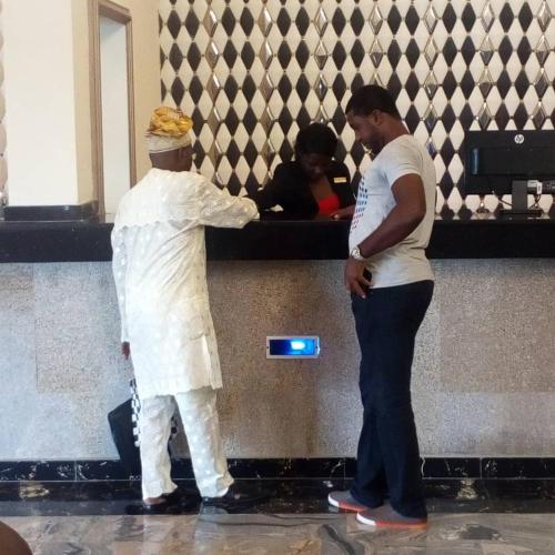 a man helping a woman at a counter at Conference Hotel , Abeokuta in Abeokuta