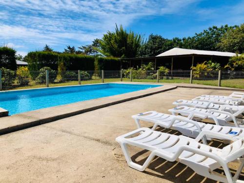 a group of white lounge chairs next to a swimming pool at Rangi Moana in Hanga Roa