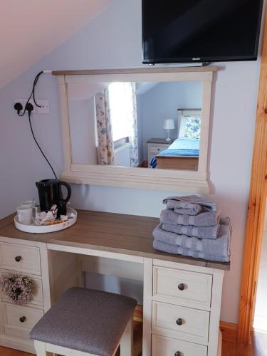 a desk with a mirror and a table with towels at Nellies Cottage B&B in Kilcogy