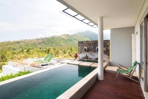 a house with a swimming pool with mountains in the background at Svarga Resort Lombok in Senggigi 