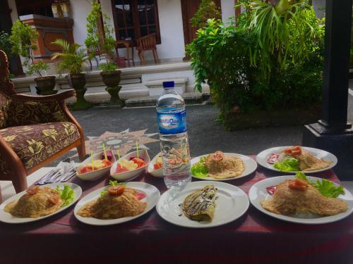 a table with plates of food and a bottle of water at Ayu Homestay in Ubud