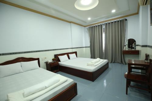 a bedroom with two beds and a table and a chair at Tina 2 Hotel in Cái Răng