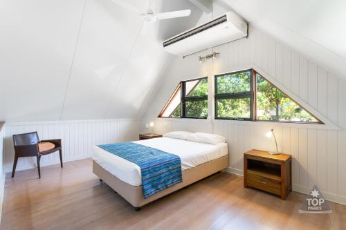Schlafzimmer mit einem Bett und einem Fenster in der Unterkunft Cardwell Beachcomber Motel & Tourist Park in Cardwell