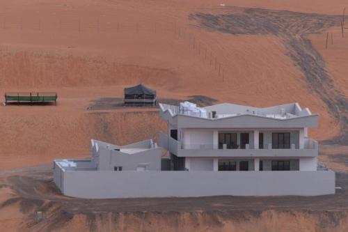 a white building in the middle of a desert at Home X4 in Al Wāşil