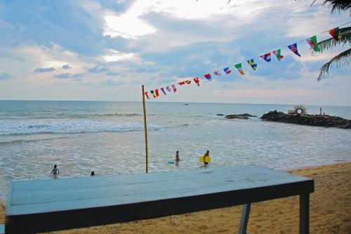 a beach with a flag and people in the water at Brother's Beach Home in Galle