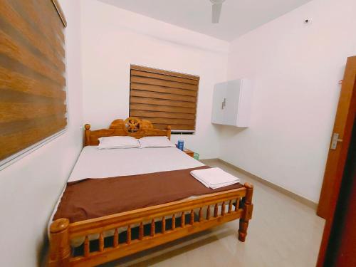 ein Schlafzimmer mit einem Holzbett und einem Fenster in der Unterkunft Corniche Beach Resort in Mulappilangād