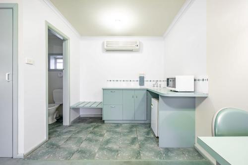 a white kitchen with a sink and a microwave at Kerang Valley Resort in Kerang