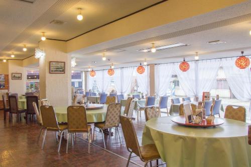a dining room with tables and chairs and windows at Lake Side Hotel Minatoya in Inawashiro