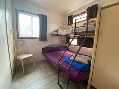 a small room with a bunk bed and a chair at Twin Dolphins Holiday Park in Tuncurry