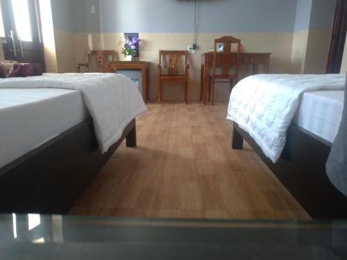 a room with two beds and a wooden floor at Khách sạn Ánh Đông in Phan Rang