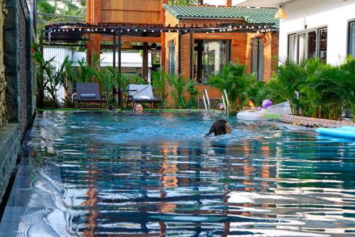 a group of people swimming in a swimming pool at Aurora House in Phu Quoc