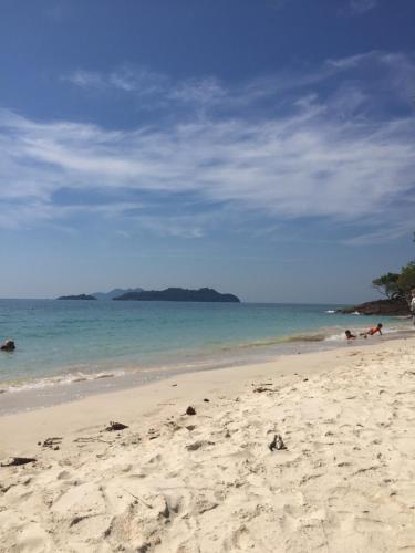a sandy beach with people swimming in the ocean at Homebar in Ko Chang