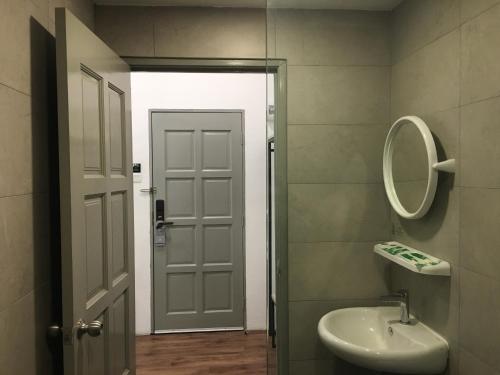 a bathroom with a sink and a mirror and a door at THE WOOD BOUTIQUE HOTEL in Muar