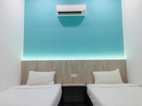 two beds in a room with a air conditioner on the wall at THE WOOD BOUTIQUE HOTEL in Muar