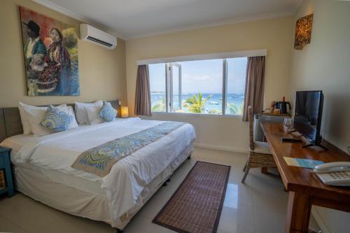 ein Schlafzimmer mit einem großen Bett, einem Schreibtisch und einem Fenster in der Unterkunft Scallywags Resort in Gili Trawangan