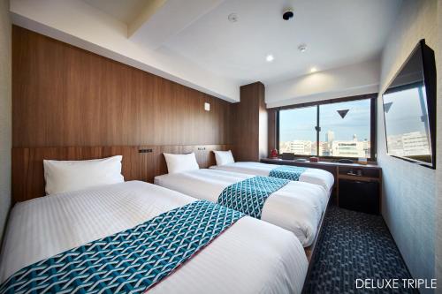 une chambre d'hôtel avec trois lits et une fenêtre dans l'établissement HOTEL AMANEK Asakusa Ekimae, à Tokyo