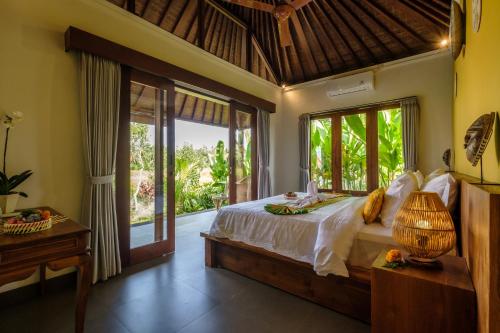 een slaapkamer met een bed in een kamer met ramen bij A home, like a dream in Ubud