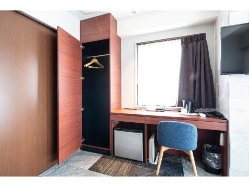 a desk with a blue chair and a window at Place Hotel Ascot in Kumamoto