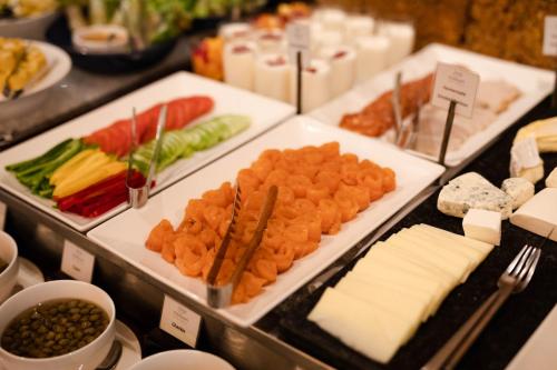 a buffet of food with cheese and vegetables on trays at Jaya House River Park Hotel in Siem Reap