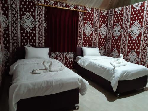 two beds in a room with red and white wallpaper at Sand Star Camp in Wadi Rum